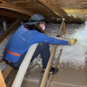 Technician adding blown-in fiberglass insulation to a garage attic in Gilbert, Arizona to improve comfort and reduce heat.