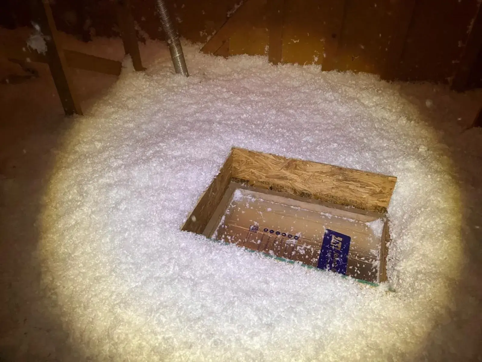 An insulated and sealed attic access hatch with a dam to hold back blown-in insulation.
